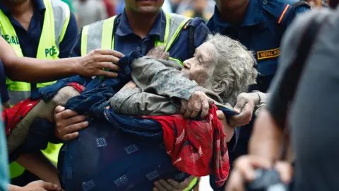 Rescuers transport an elderly woman rescued from flooded area