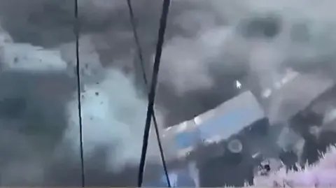 A lorry being swept away on its side