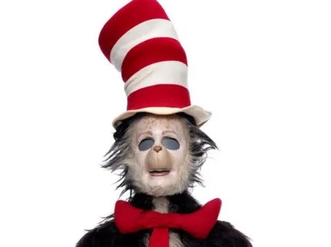 Propstore A screengrab of the original Cat in the Hat suit from the 2003 Mike Myers film, it features a tall red and white top hat and a red tie and is showing noticeable signs of disrepair. 